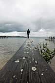  Man on a jetty at Lake Chiemsee, Bavaria, Germany 