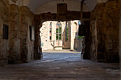  Stone arch leading to the sunlit courtyard, ruins of St. Aegidius Church, Hanover, Germany 
