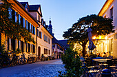  Schiffstraße with historic Huguenot houses, street cafes and view of the Old Town Church in the evening light in Erlangen, Middle Franconia, Franconia, Bavaria, Germany 