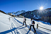  Two women with snowshoes hiking towards alpine huts, Val da Camp, Livigno Alps, Graubünden, Switzerland 