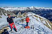  Two people on ski tour preparing for the descent, Felskarspitze, Niedere Tauern, Salzburg, Austria 
