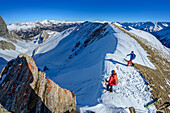  Two people on ski tour preparing for the descent, Felskarspitze, Niedere Tauern, Salzburg, Austria 