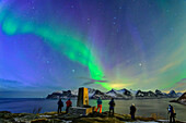  Several photographers stand at the summit of Knuten and look at the Northern Lights over Mefjord, Knuten, Senja, Troms, Norway 