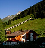  View over an alpine house to alpine meadows and the Allmendhubel cable car in the morning light, Mürren, Lauterbrunnen, Bernese Oberland, Switzerland 