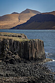 Basalt Steilküste auf der kleinen Insel Ulva. Berge im Hintergrund, Schottland, Großbritannien