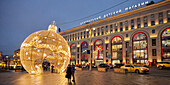 People taking pictures in front of illuminated Christmas tree ball in the historic center of Moscow, Russia.
