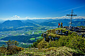  Two people hiking at the summit cross of Hundsalmjoch with Inntal valley in the background, Hundsalmjoch, Rofan, Tyrol, Austria 