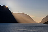  The morning sun appears behind the mountain in golden light, Prins Christian Sound, Kujalleq, Greenland, Europe 