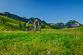  Man and woman mountain biking with the Wendelstein mountain in the background, around the Wendelstein, Mangfall Mountains, Bavarian Alps, Upper Bavaria, Bavaria, Germany 