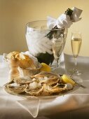 Plate of oysters & lemon on ice, bread & champagne on table