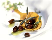 Dunkle Oliven mit Olivenöl auf Holzlöffel