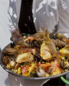 Person hält gemischte Paella