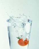 Tomato falling into a water glass