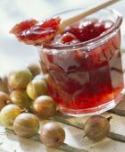 Stachelbeermarmelade im Glas und auf Holzlöffel