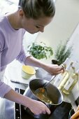 Young woman stirring soup pan on stove