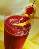 Raspberry drink in glass, with raspberry & lemon peel garnish