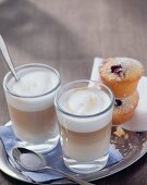 Zwei Gläser Latte Macchiato und Muffins auf einem Tablett