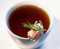 Game stock in a bowl with garlic and rosemary