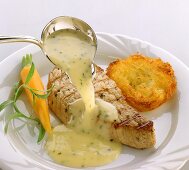 Pouring white wine sauce over grilled salmon steak
