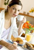 Junge Frau mit Kaffee am Frühstückstisch
