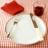 Place-setting for one with red wine on checked tablecloth