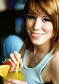 Freckled young woman with fruit cocktail