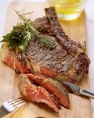 Peppered steak on a wooden board, cutlery beside it