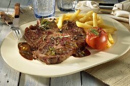 Peppered T-bone steak with chips and baked tomato