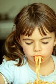 Mädchen isst Spaghetti mit Tomatensauce