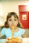 Girl eating spaghetti with tomato sauce (grainy effect)