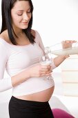 Schwangere Frau schenkt sich Milch in ein Glas