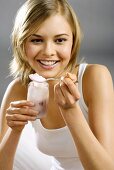 Young woman with yoghurt jar and spoon