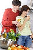 Young couple standing in kitchen, with beer glasses