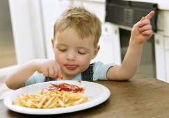 Kleiner Junge beim Pommes essen