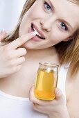 Young woman rubbing honey into her lips