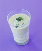 Avocado soup in glass with parsley on violet background