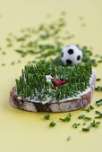 Miniature footballer mowing bread & butter with chives