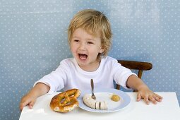 Small boy with Weisswurst sausage and pretzel