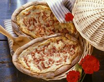 Two tartes flambées with bacon & onions in basket