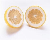 Two pomelo halves (cross-section) on white background