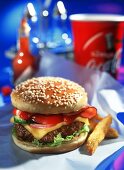 Cheeseburger mit Speck und zwei Pommes frites auf Papier