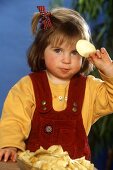 Kleines Mädchen hält Kartoffelchip in der Hand