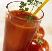 Potato and tomato drink in a glass, two tomatoes beside it