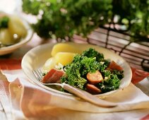 Kale with bacon, sausage and potatoes on plate