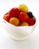 Plums of various colours in white bowl