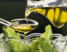 Olivenöl über Löffel auf Salat gießen