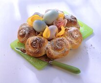 Osterkranz mit Rosen und bunten Eiern auf Schneidebrett