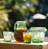 Iced tea with lemon in glass jug on table; glasses; ice bucket