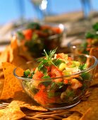 Raw tomato salsa with peppers in glass dish; tortilla chips