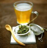 Green tea in glass cup and tea leaves in strainer